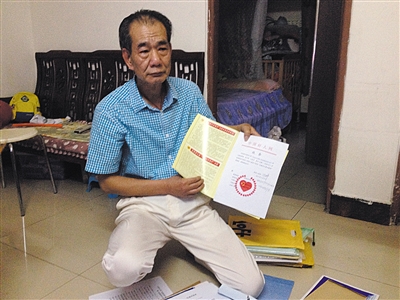 翻出一家網(wǎng)站贈(zèng)予的“中國好人”證書，區(qū)少坤單膝跪在地上，“你看，我是中國好人啊?！?范春旭 攝