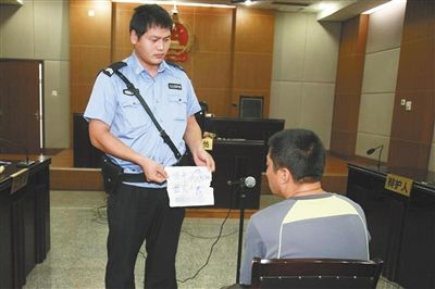 昨日庭審中，法警向趙某出示其扎完車(chē)胎后所留辱罵公司的紙條。通訊員 李秀文 攝