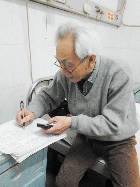 杜修源老人埋頭寫著特殊的“日記”。 李卓 攝
