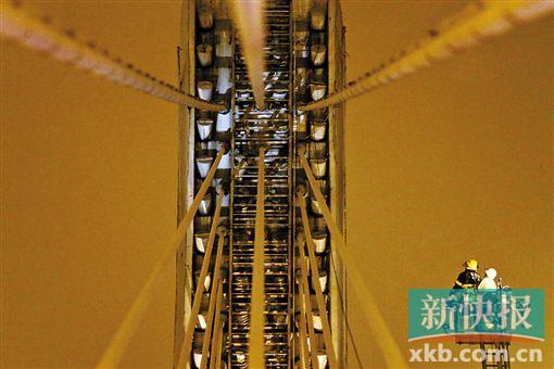 截至今日零時(shí)，男子仍未有下橋舉動(dòng)。圖為公安和消防人員乘消防云梯在高空上和男子交談。