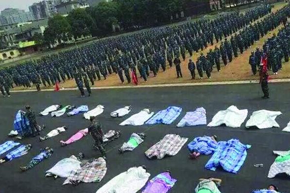 20多名女生躺在瀝青跑道上，身上嚴嚴實實地裹著棉被，接受太陽的照曬。