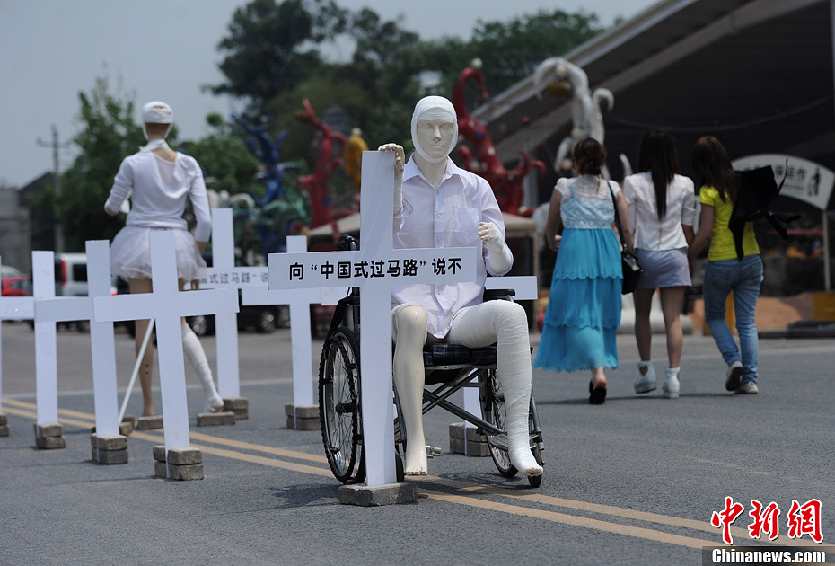4月16日，重慶市洋人街上擺放著兩個(gè)受了傷的塑料人像“模特”，旁邊十字架上寫著向“中國式過馬路”說不