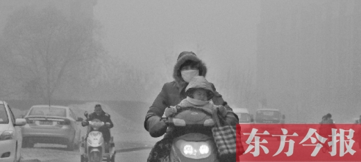 12月8日，鄭州市未來(lái)路上，一位市民帶著孩子在霧中騎行
