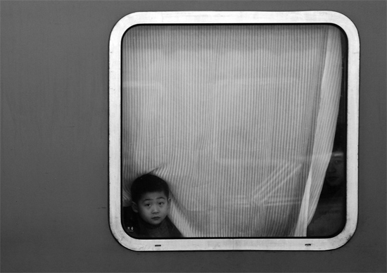 一個孩子把頭伸向窗外，他想再看送別的親人一眼