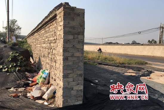 一墻之隔，一邊是道路，一邊是垃圾和荒草，市民質(zhì)疑其為遮羞墻。