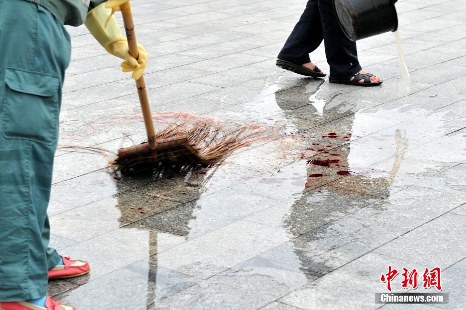 圖為環(huán)衛(wèi)工人在清理案發(fā)地點(diǎn)的血跡。