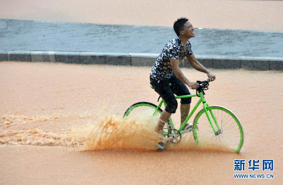 5月11日，一名行人在深圳街頭冒雨騎行。