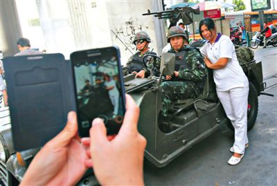 20日，泰國首都曼谷，一名婦女與執(zhí)行軍管任務的士兵合影。