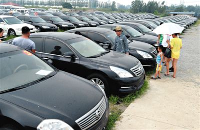 昨日，市民在山東棗莊一家拍賣公司場地上查看待拍賣公車。當(dāng)日，棗莊市103輛公車公開拍賣。新華社記者