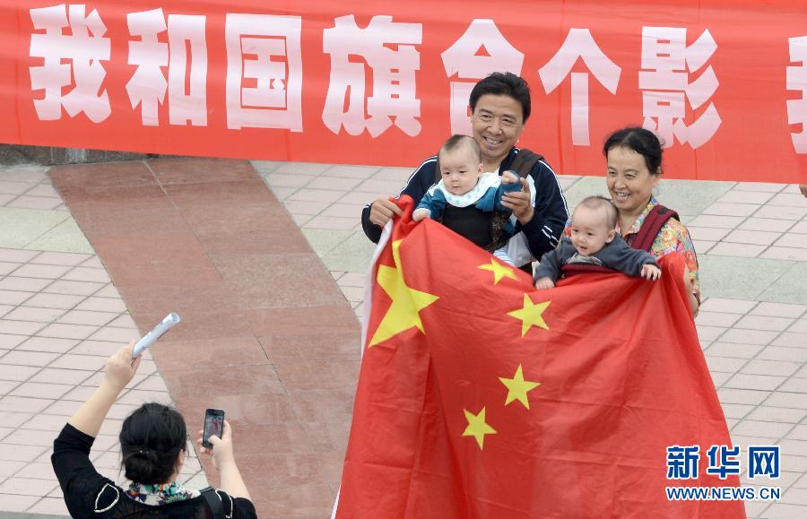 9月27日，在山東德州市中心廣場(chǎng)，市民與國旗合影。