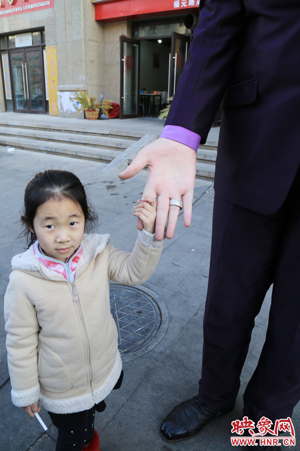 巨人“張歡”牽著一名漂亮的小女孩，兩人的手大小對(duì)比非常明顯。
