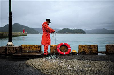7月6日，韓國珍島，一名海岸警察在港口系救生圈。4月，客輪在珍島近海發(fā)生沉船事故后，仍有11人下落不明。