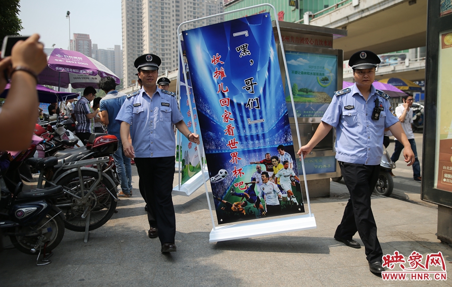 7月2日上午，鄭州市紫荊山地鐵站出入口，執(zhí)法人員抬著寫有勸導(dǎo)語的宣傳板，前往占道經(jīng)營攤位“圍觀執(zhí)法”